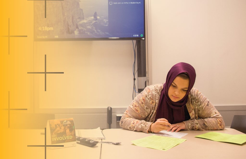 Woman working on a study room at a table with papers on it.