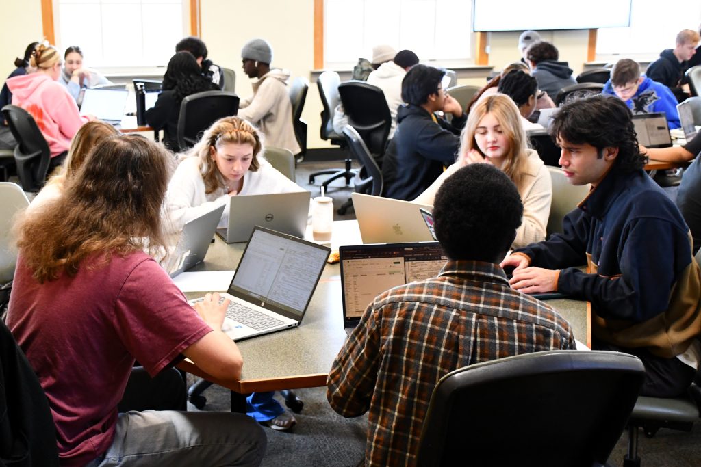 students working in small groups at multiple tables throughout the classroom
