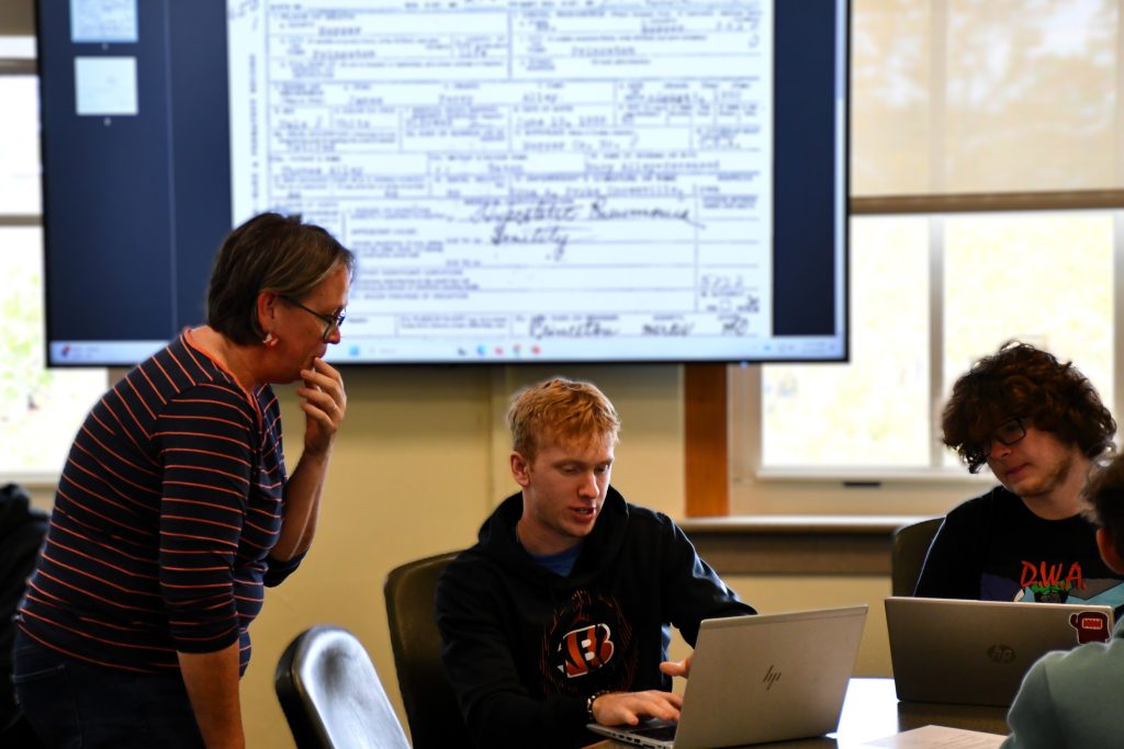 Faculty member Carolyn Orbann interacts with students working on laptops during research project