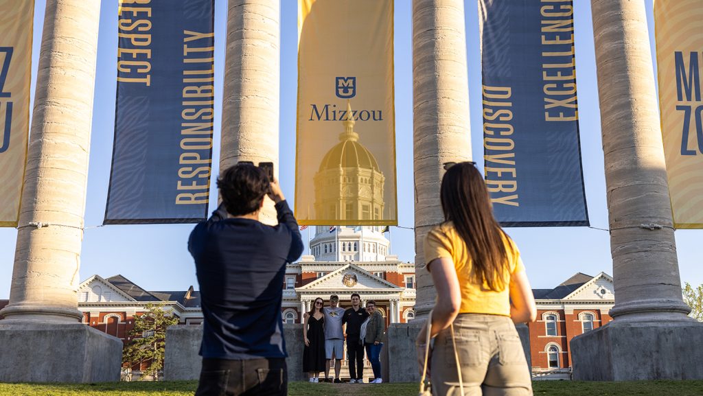 Students taking photos by columns at graduation