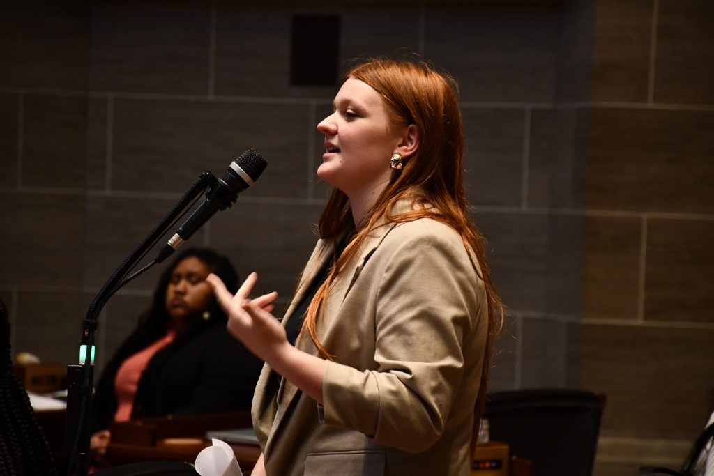 female high school student speaks at a microphone