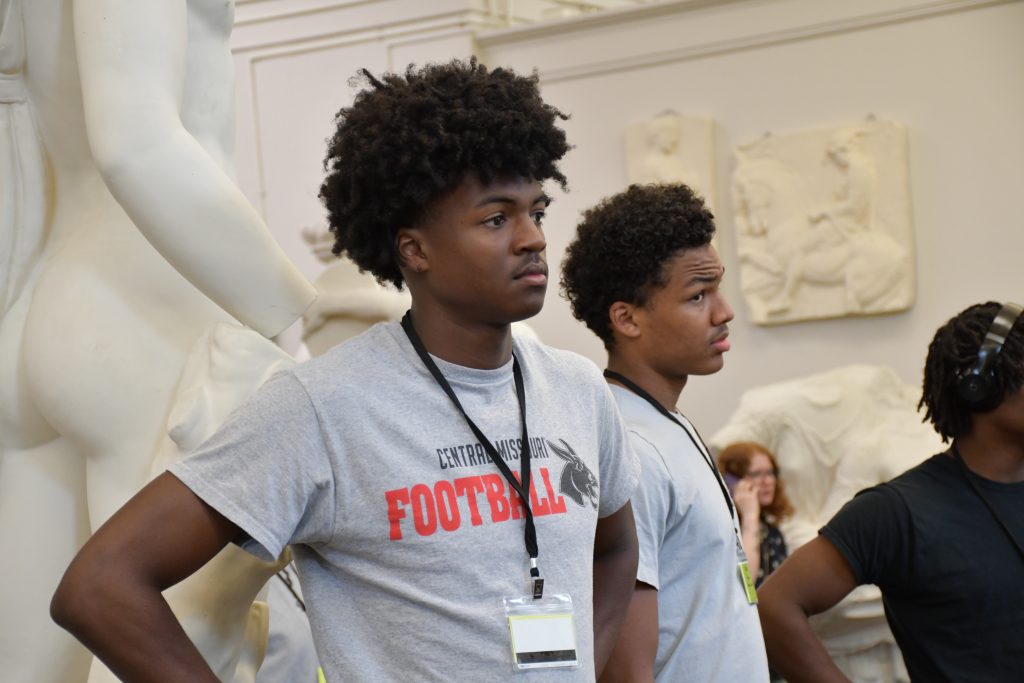 Two male high school students observing cast statues in a museum