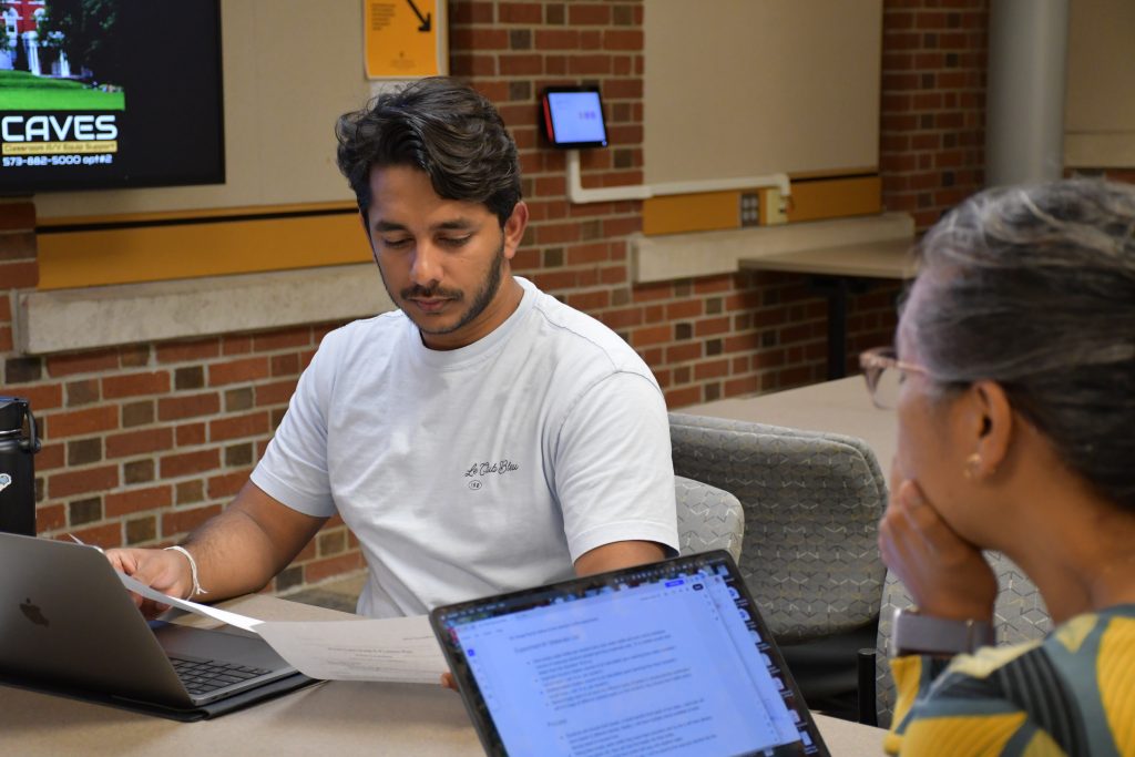male college student reviews notes with a female staff member