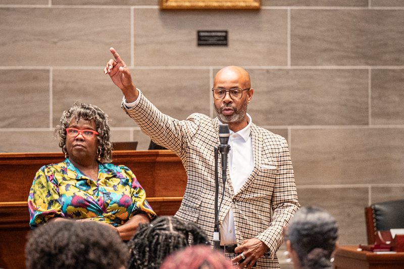 Two legislators speak from a microphone