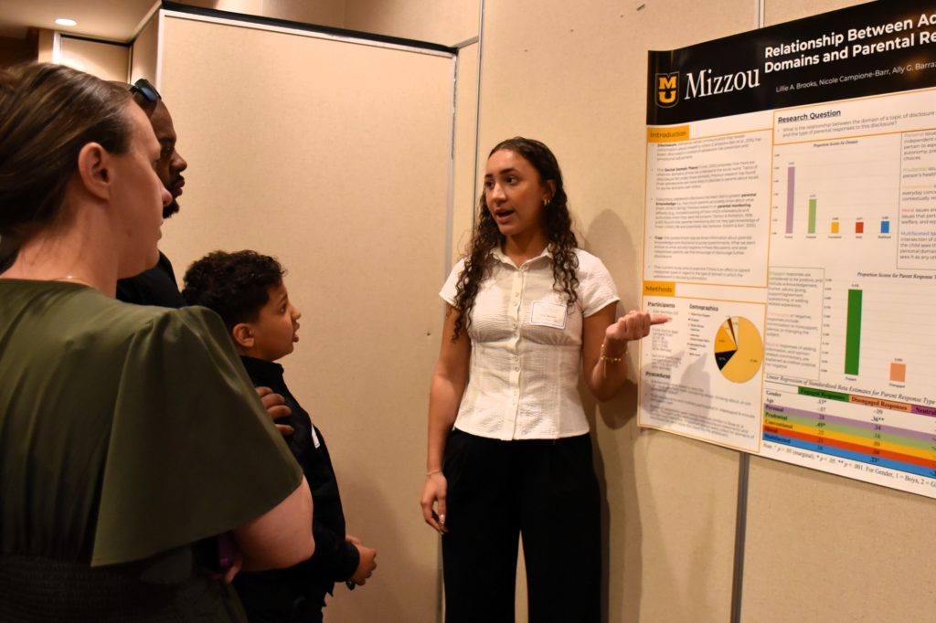 female scholar giving a poster presentation to small audience